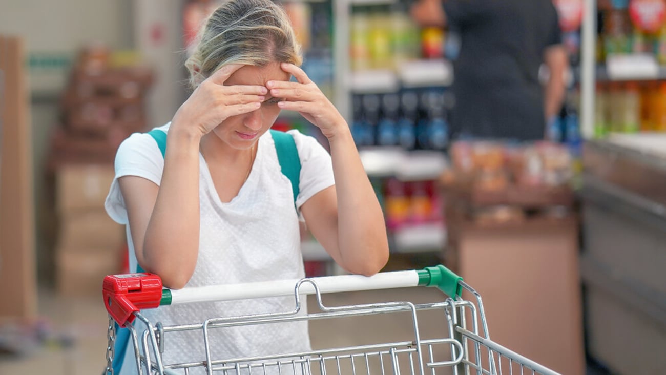 Upset woman in a supermarket with an empty shopping trolley. Crises, rising prices for goods and products. Woman shopping at the supermarket.                              ; Shutterstock ID 1553166797