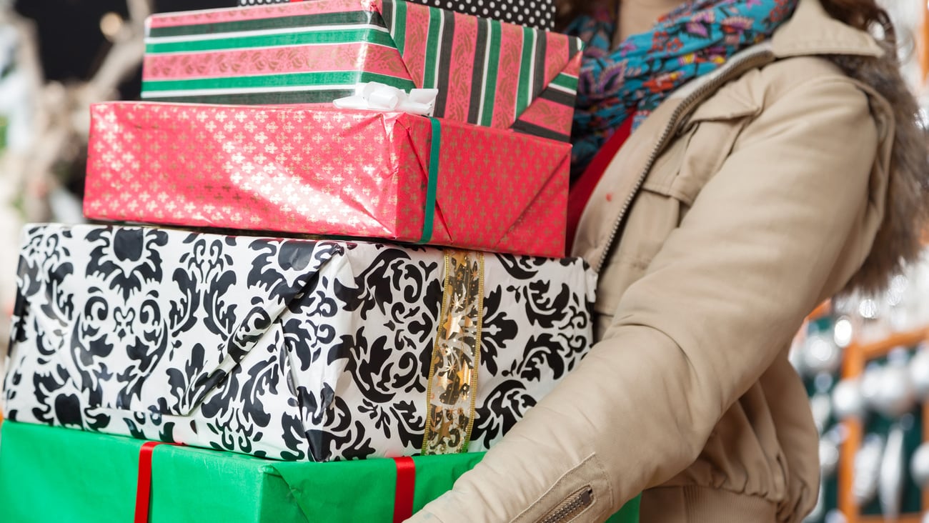 Midsection of young woman carrying stacked Christmas gifts in store; Shutterstock ID 155641259