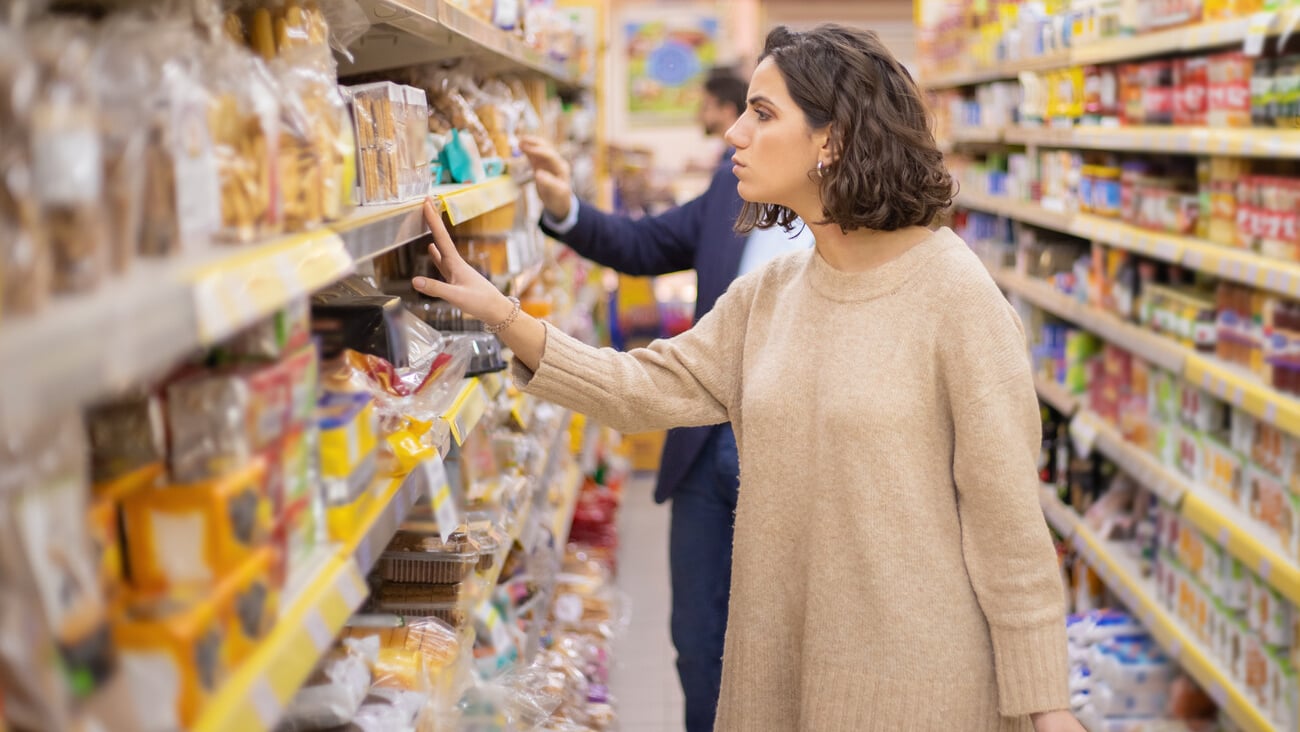 Serious woman looking at cookies in grocery store. Side view of people choosing baked goods in supermarket, selective focus. Shopping concept; Shutterstock ID 1664636539