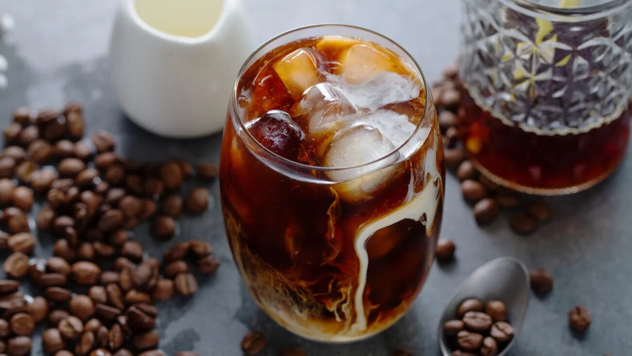 Tasty refreshing iced coffee with ice cubes in glasses on bright background. Closeup; Shutterstock ID 2025940094