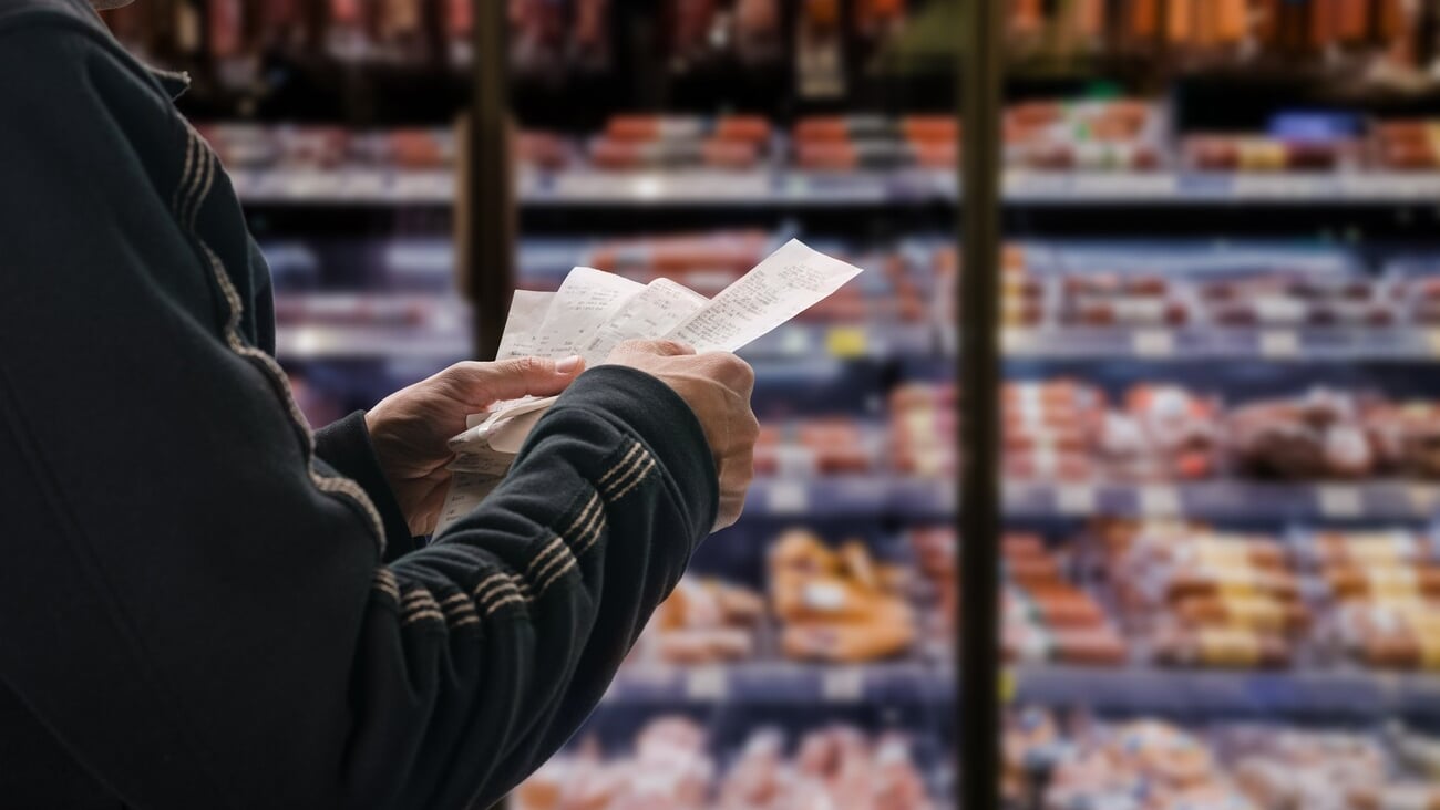 Minded man viewing receipts in supermarket and tracking prices; Shutterstock ID 2067795809