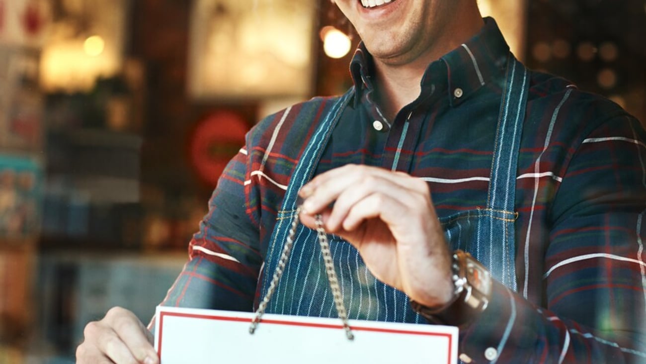 Open sign, smile and man with business, startup success and service with restaurant, window and coffee shop. Male person, employee and entrepreneur with billboard, poster and opening retail store; Shutterstock ID 2304304625