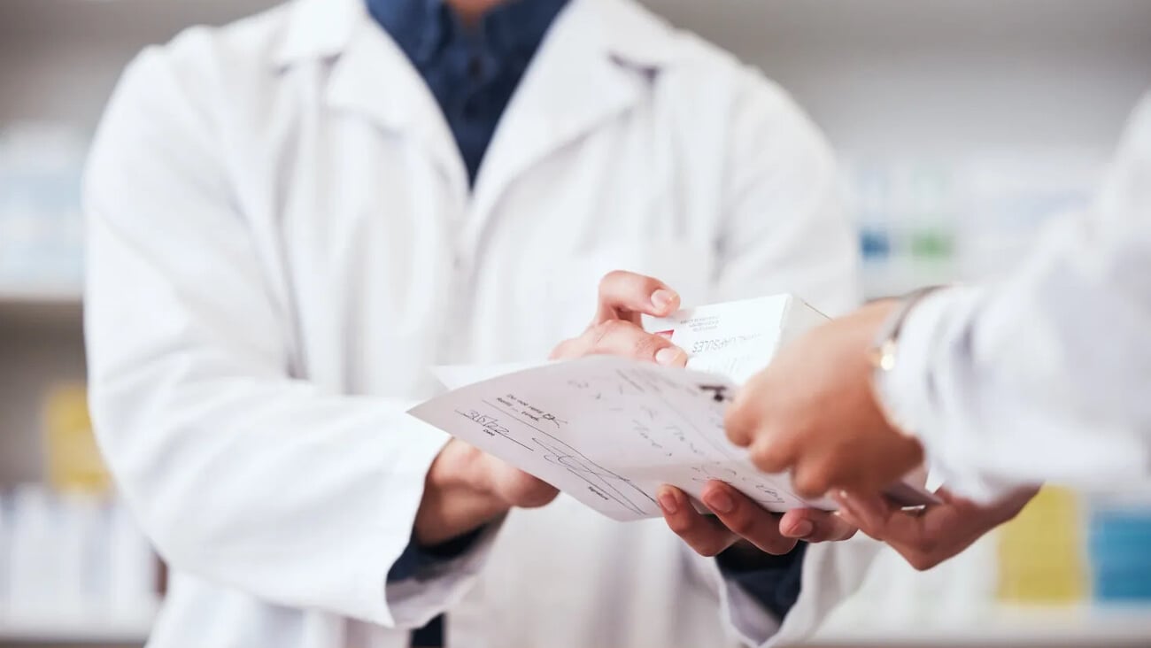 Healthcare, pharmacy and prescription medicine in hand of customer with paper, box or rx medication. Closeup of pharmacist or medical staff with person for pharmaceutical product at retail drugstore; Shutterstock ID 2353169745