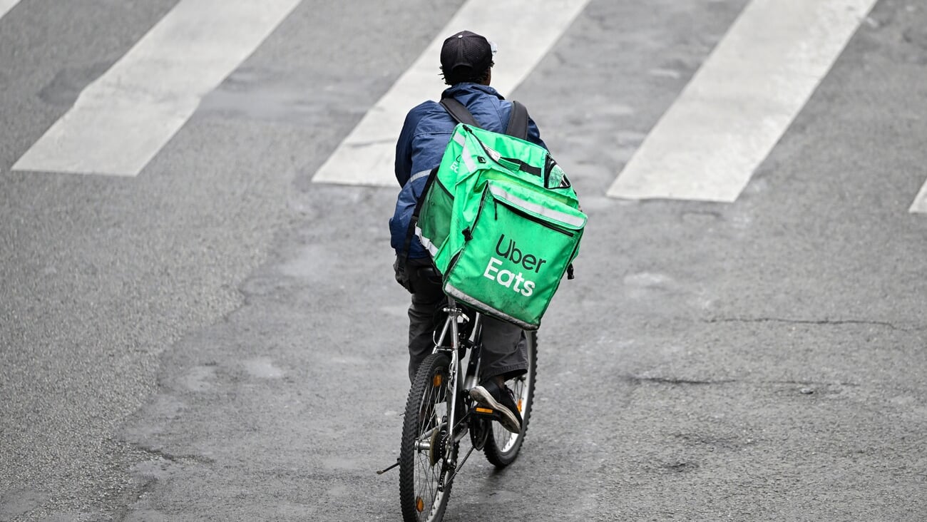 A deliver for Uber Eats or UberEats on his bike or bicycle. Illustration of delivers for home food meal takeaway delivery platforms, in Paris, France on October 19, 2023.; Shutterstock ID 2382852033