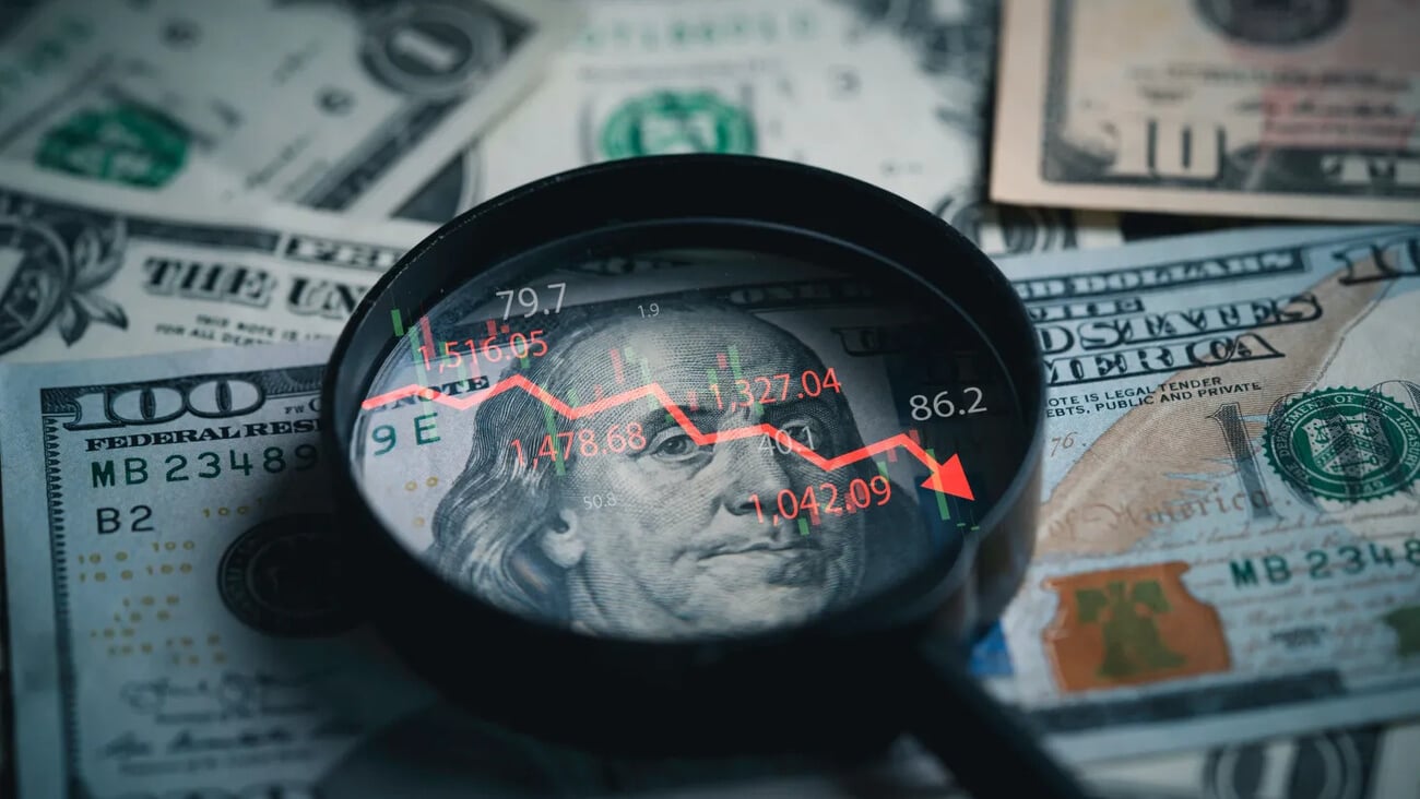 Red down arrow inside of magnifier glass and USD dollar banknote for United States of America or USA economic recession concept.; Shutterstock ID 2501604651