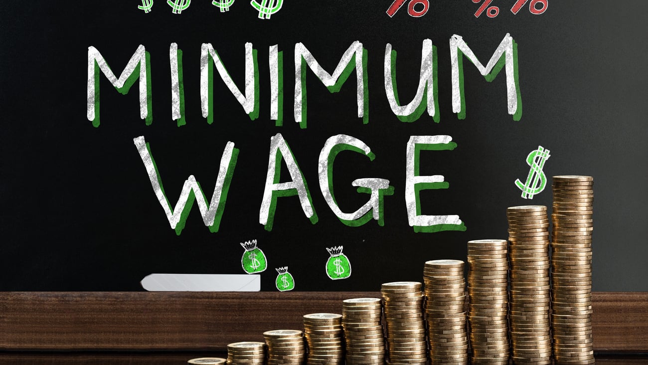 Minimum Wage At Blackboard Behind Stacked Coins; Shutterstock ID 707531416