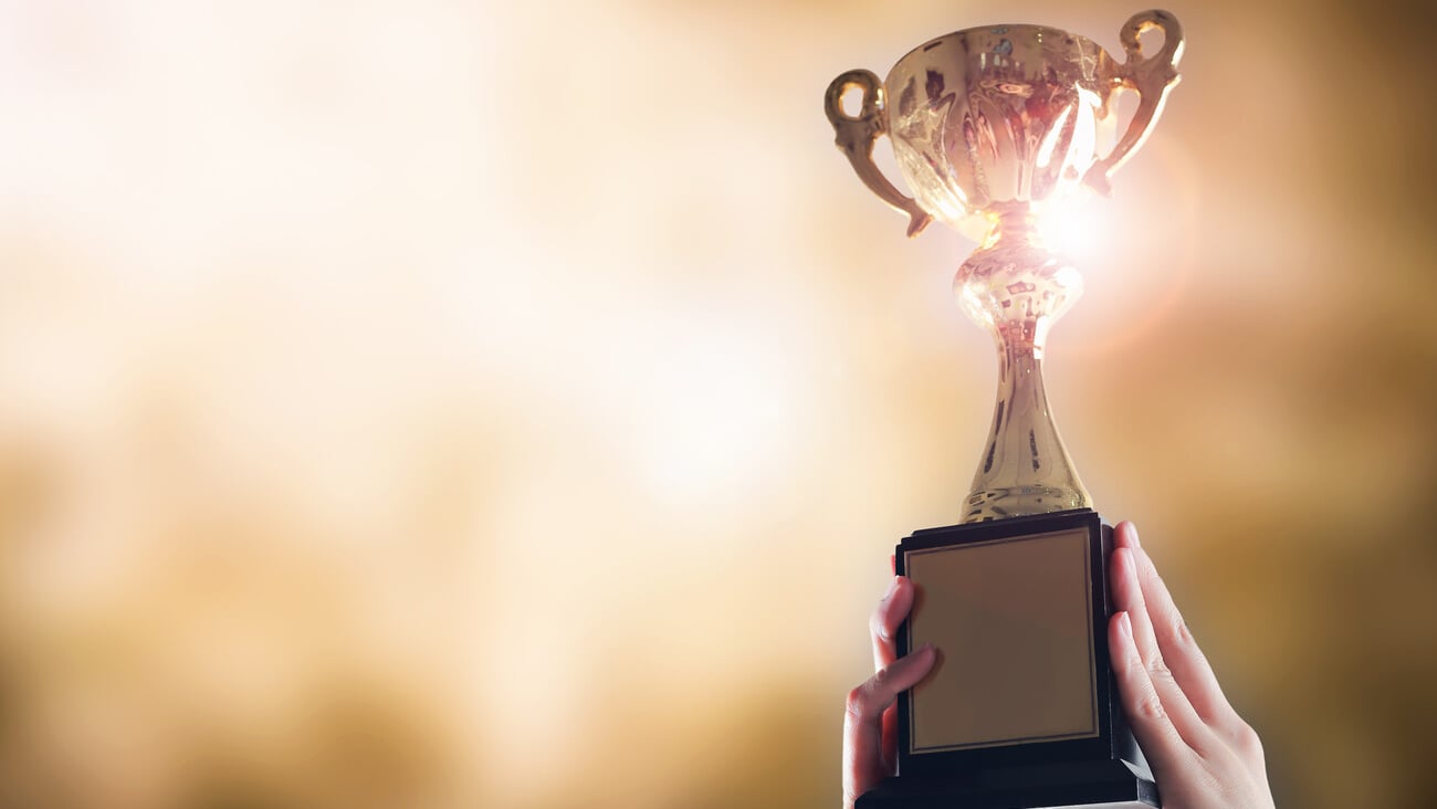 Hands holding trophy cup on gold blurry bokeh background.; Shutterstock ID 1034397511