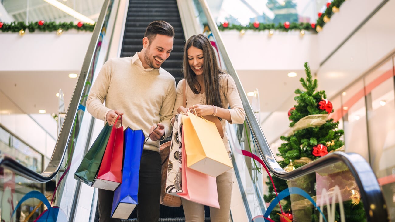 Romantic Christmas shopping.Sale, technology and people concept - happy young couple with shopping bags.Image taken inside a shopping mall.Selective focus; Shutterstock ID 356223023