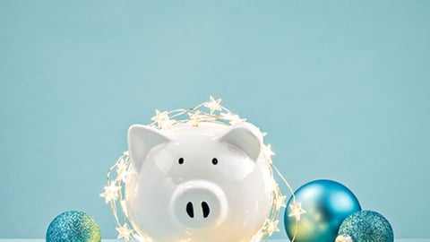 Piggy bank wrapped in a string of Christmas lights