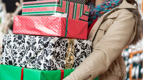 Midsection of young woman carrying stacked Christmas gifts in store; Shutterstock ID 155641259