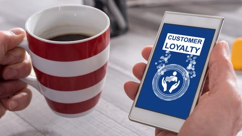 Male hand holding a smartphone with customer loyalty concept; Shutterstock ID 1998327014