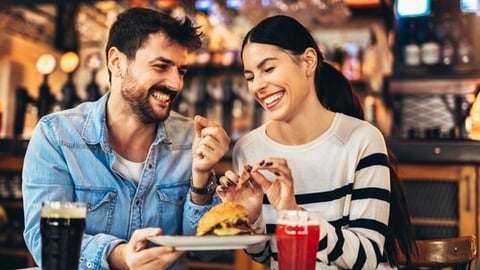 Young couple in love having fun spending leisure time together at restaurant, eating burgers and drinking beer; Shutterstock ID 2240724321