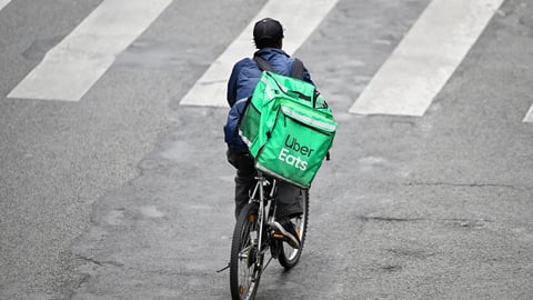 A deliver for Uber Eats or UberEats on his bike or bicycle. Illustration of delivers for home food meal takeaway delivery platforms, in Paris, France on October 19, 2023.; Shutterstock ID 2382852033