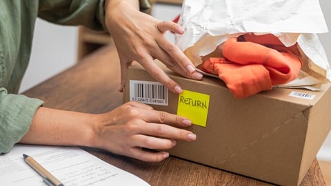 woman online shopper affixes a barcode sticker to a cardboard box, marking it for return and refund. ; Shutterstock ID 2391610675