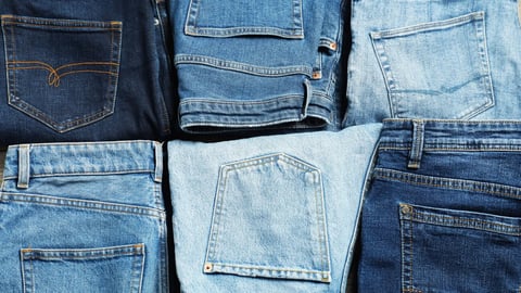 Different stylish jeans as background, top view; Shutterstock ID 2608221783