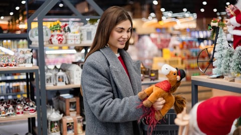 Woman choosing a toy horse decoration in a holiday store. Symbol of the 2026 Year of the Horse, seasonal shopping and festive preparations.; Shutterstock ID 2706897233