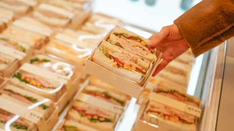 Hand Holding Packaged Sandwich in Display Case; Shutterstock ID 2720437709