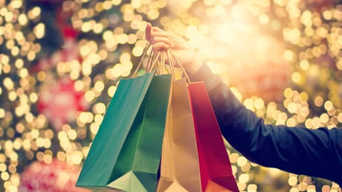 Christmas shopping bags in hand on christmas decoration and light on street background; Shutterstock ID 757967017