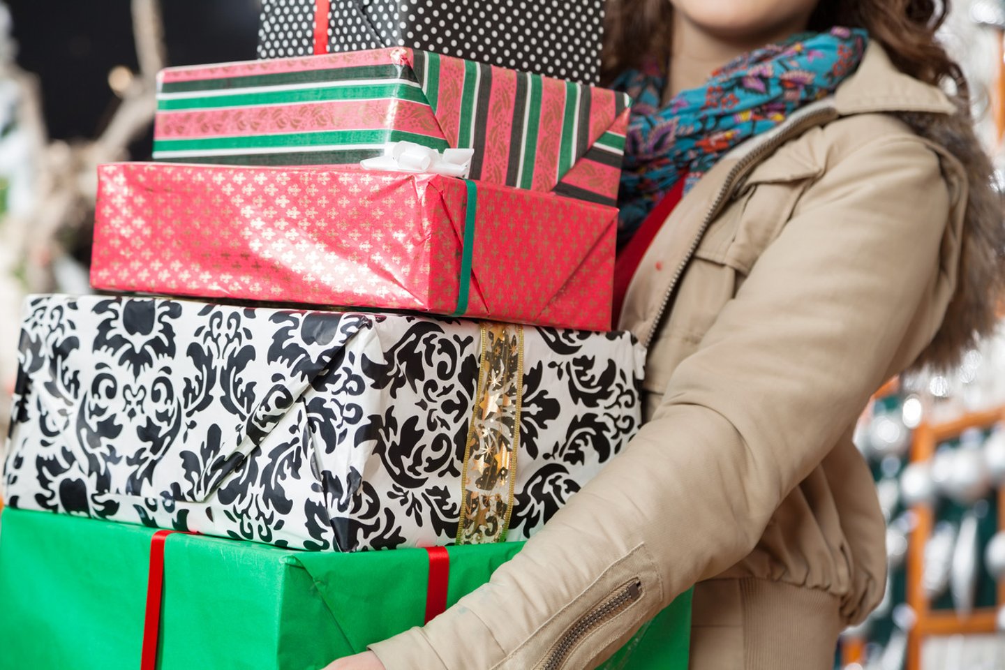 Midsection of young woman carrying stacked Christmas gifts in store; Shutterstock ID 155641259