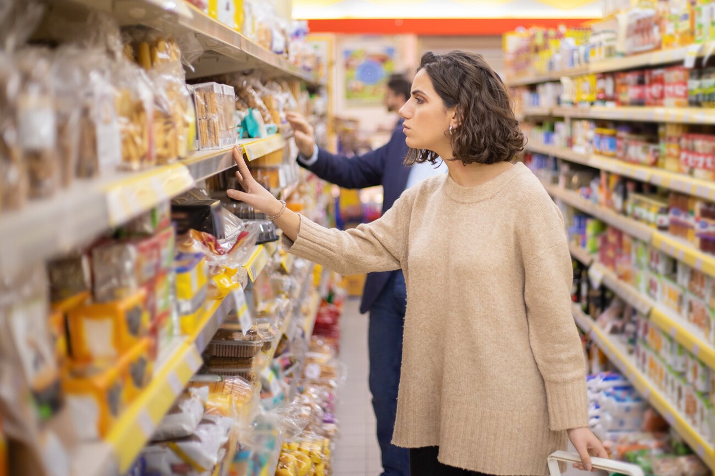 Serious woman looking at cookies in grocery store. Side view of people choosing baked goods in supermarket, selective focus. Shopping concept; Shutterstock ID 1664636539