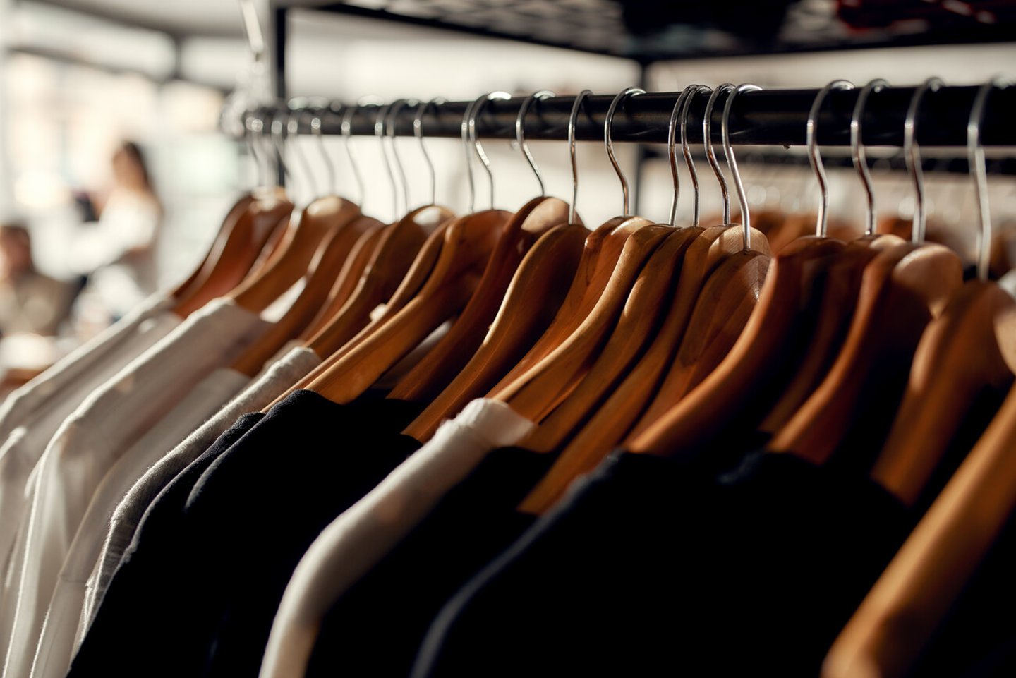 Close up of clothes rack or rail in the store. Items at custom T-shirt, clothing printing company. Horizontal shot; Shutterstock ID 1727723350