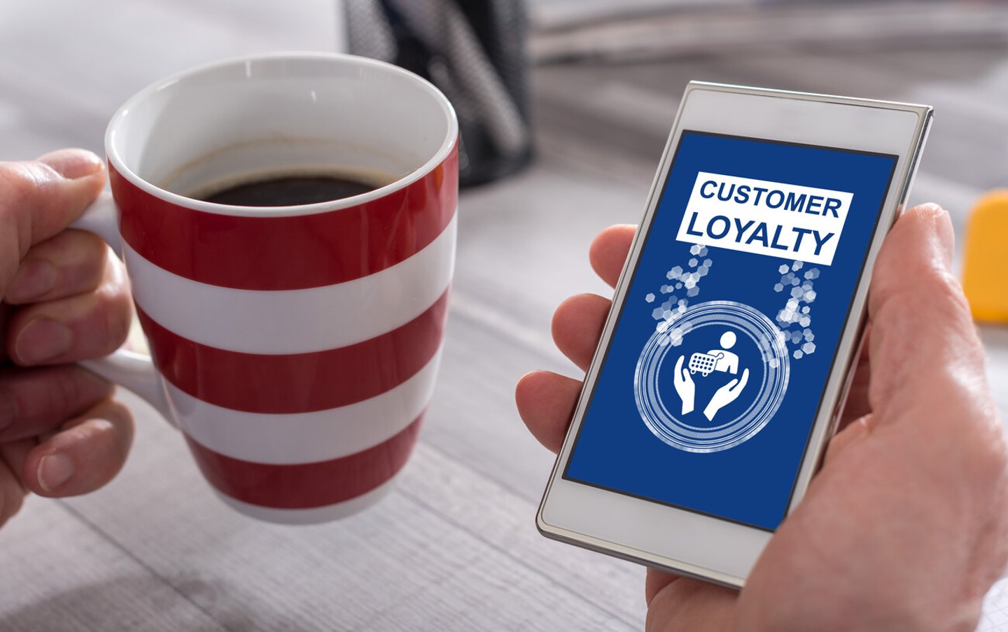 Male hand holding a smartphone with customer loyalty concept; Shutterstock ID 1998327014