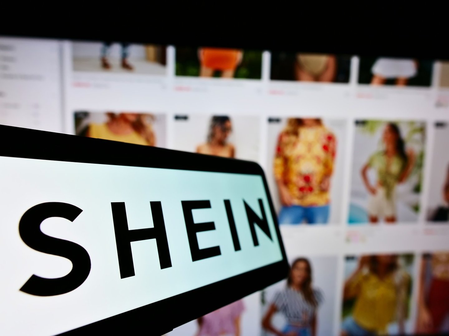 STUTTGART, GERMANY - Aug 14, 2021: Mobile phone with logo of Chinese e-commerce company Shein on screen in front of business website Focus on center-left of phone display ; Shutterstock ID 2037893222