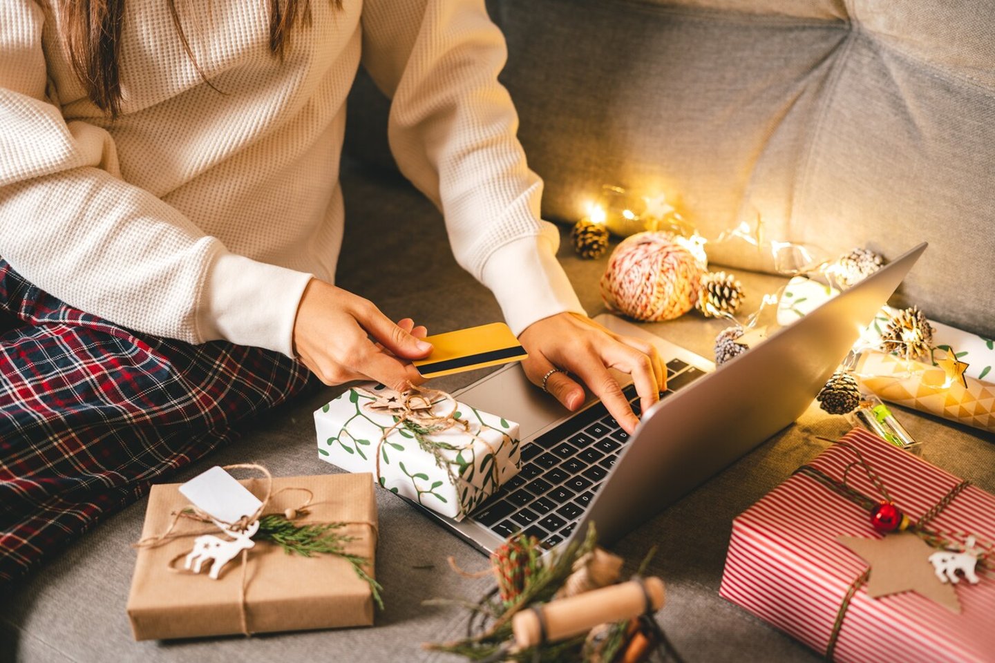 Close up of woman hands with credit card, gifts, and laptop. Online shopping at Christmas holidays. Cropped female sit on couch with natural eco presents and decor. Merry Christmas packing Concept.; Shutterstock ID 2067652718