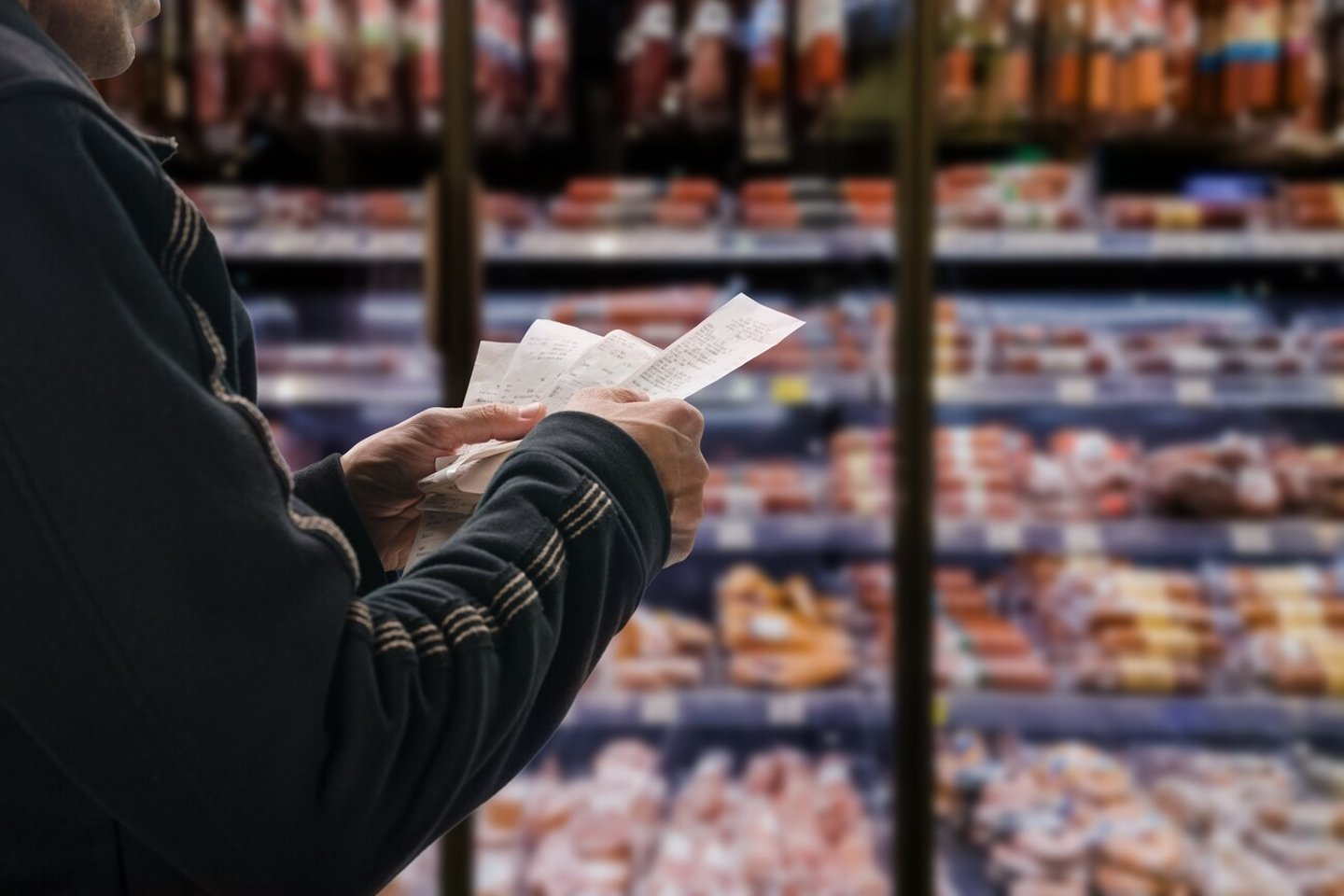 Minded man viewing receipts in supermarket and tracking prices; Shutterstock ID 2067795809