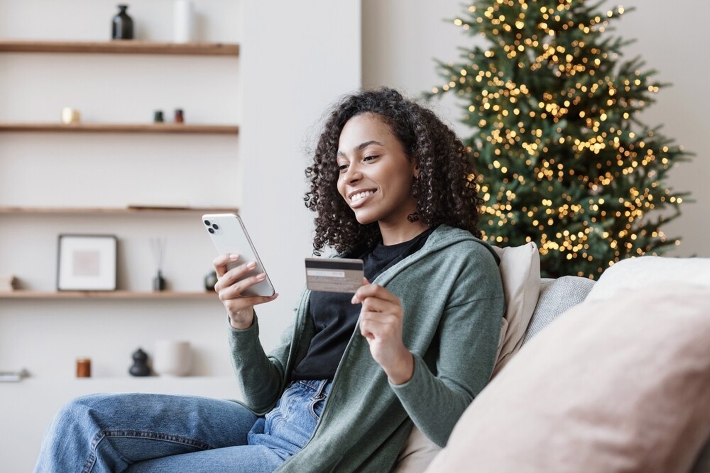 Shopping online during holidays. Woman using smartphone and credit card, ordering Christmas gifts. Online shopping, e-commerce, internet banking, spending money concept; Shutterstock ID 2220883709