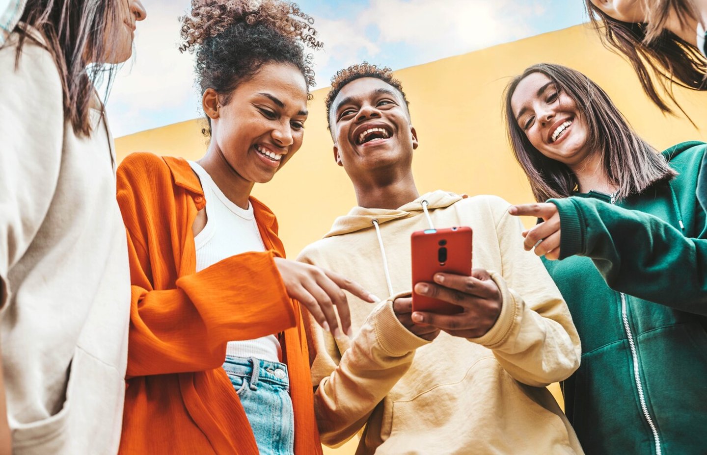 Diverse young people using smart mobile phone device outdoors - Multiracial friends watching smartphone together - Teenagers uploading reel video on social media platform - Youth culture concept; Shutterstock ID 2275871901