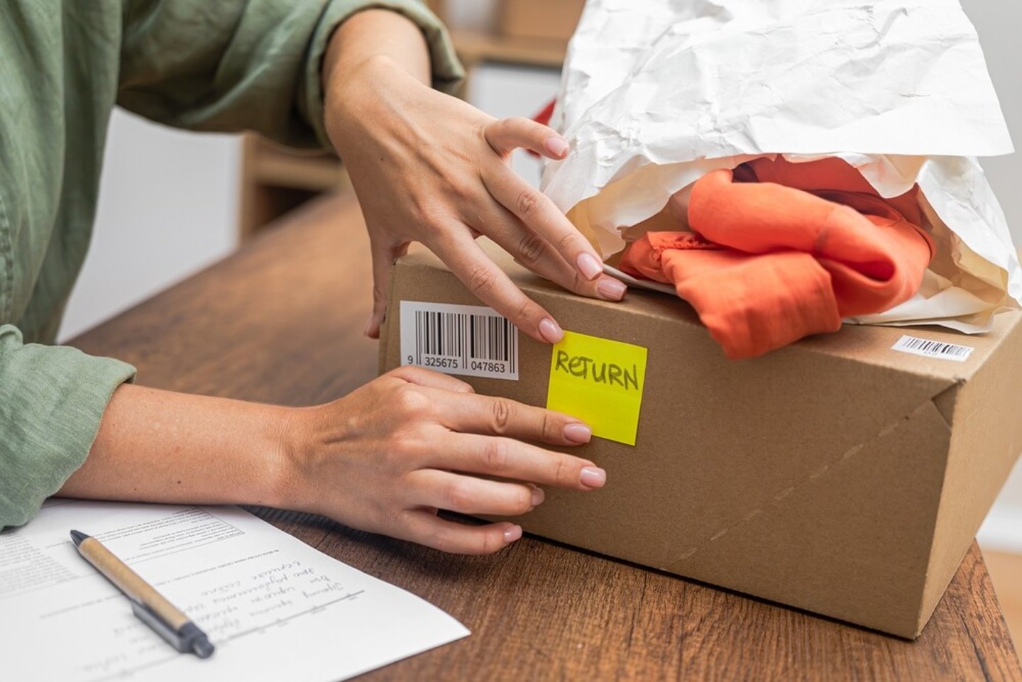 woman online shopper affixes a barcode sticker to a cardboard box, marking it for return and refund. ; Shutterstock ID 2391610675