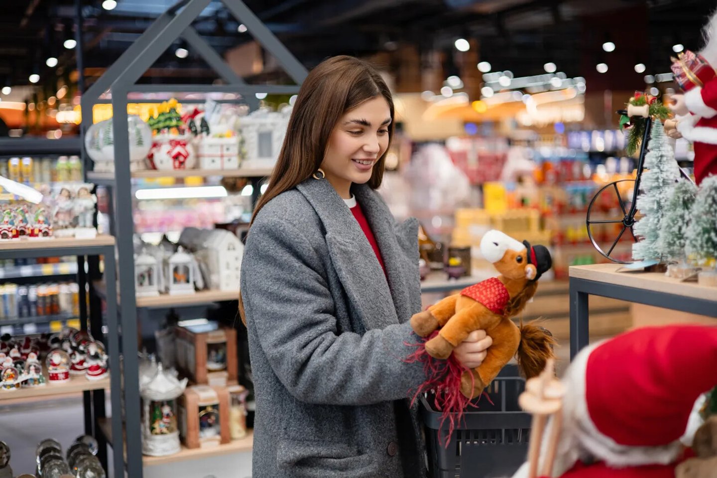 Woman choosing a toy horse decoration in a holiday store. Symbol of the 2026 Year of the Horse, seasonal shopping and festive preparations.; Shutterstock ID 2706897233