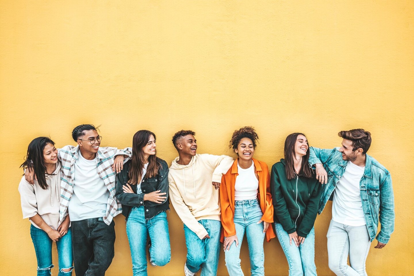 Happy multiracial friends standing over isolated background - Cheerful young people socializing outdoors - University students laughing together on yellow wall - Youth culture and friendship concept; Shutterstock ID 2244259657