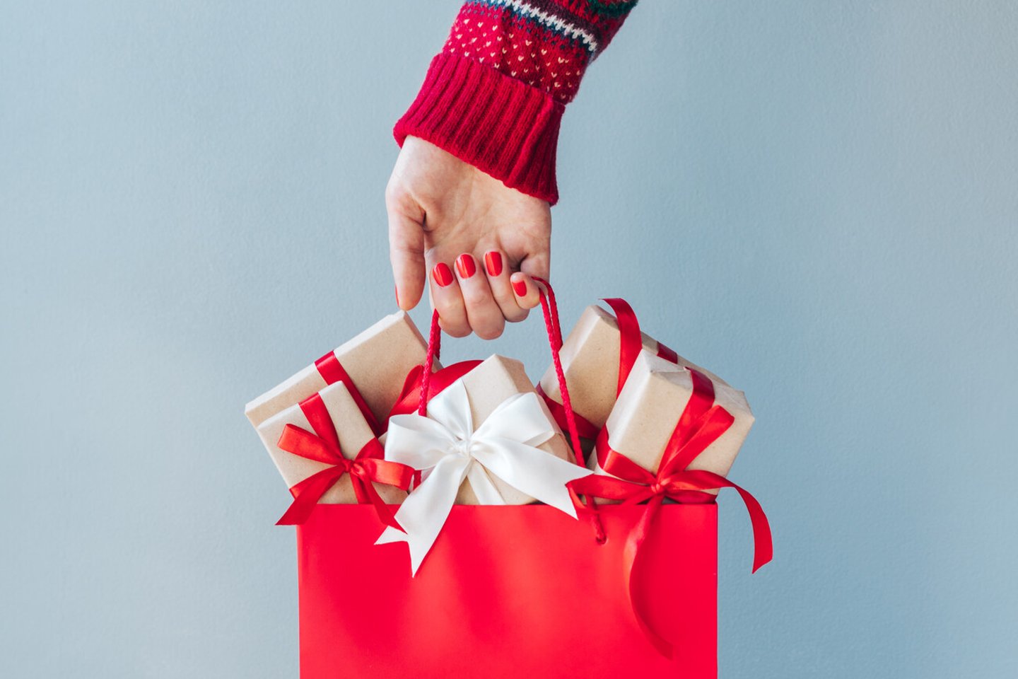 Cropped image of female hand with red polished nails holding shopping bag full of christmas gift boxes. Holiday sale concept. ; Shutterstock ID 1816229015