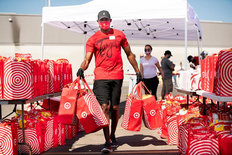 A team member carries bags of food and supplies, during a summer volunteer event held at the Lake Street store.