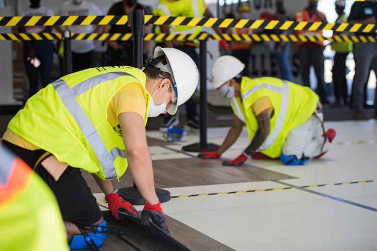 ConstructReach participants lay flooring during a volunteer event held this summer at the Lake Street store.